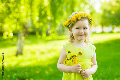 Little girl with dandelions in summer park