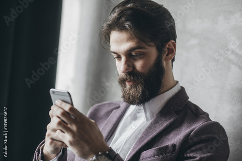 Handosme businessman with beard typing on cell phone. photo