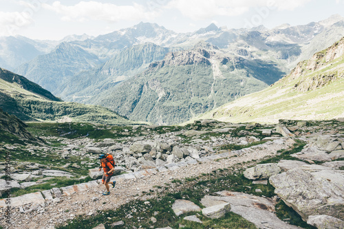 Hiker with backpack running on a mountain trail photo