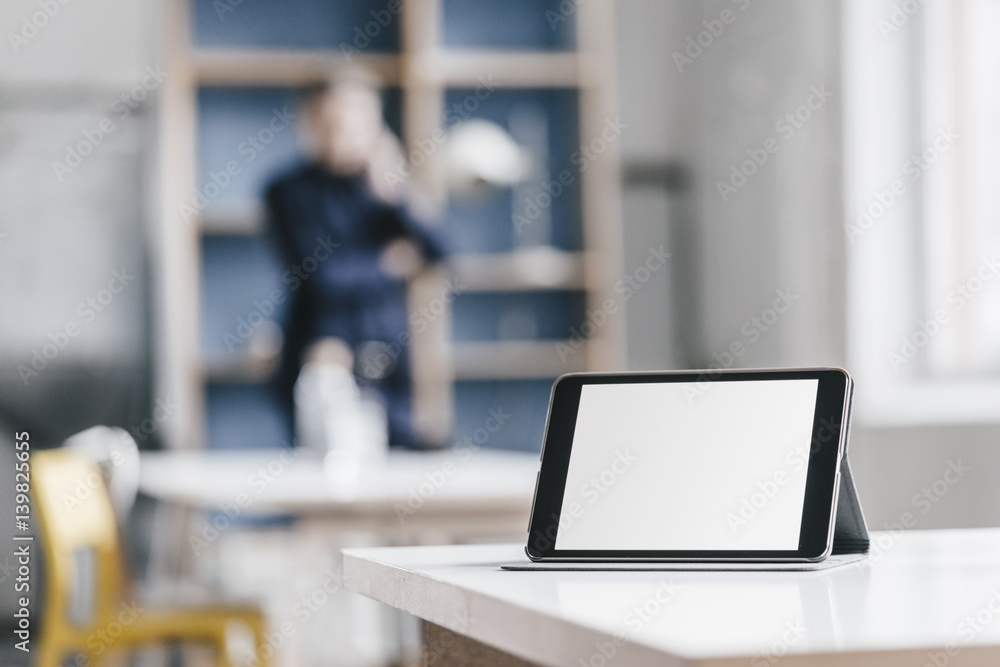 Tablet in office with businessman in background Tablet in office with businessman in background