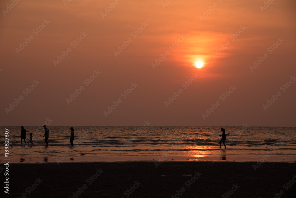 silhouette people playing on beach in the sea on sunset background