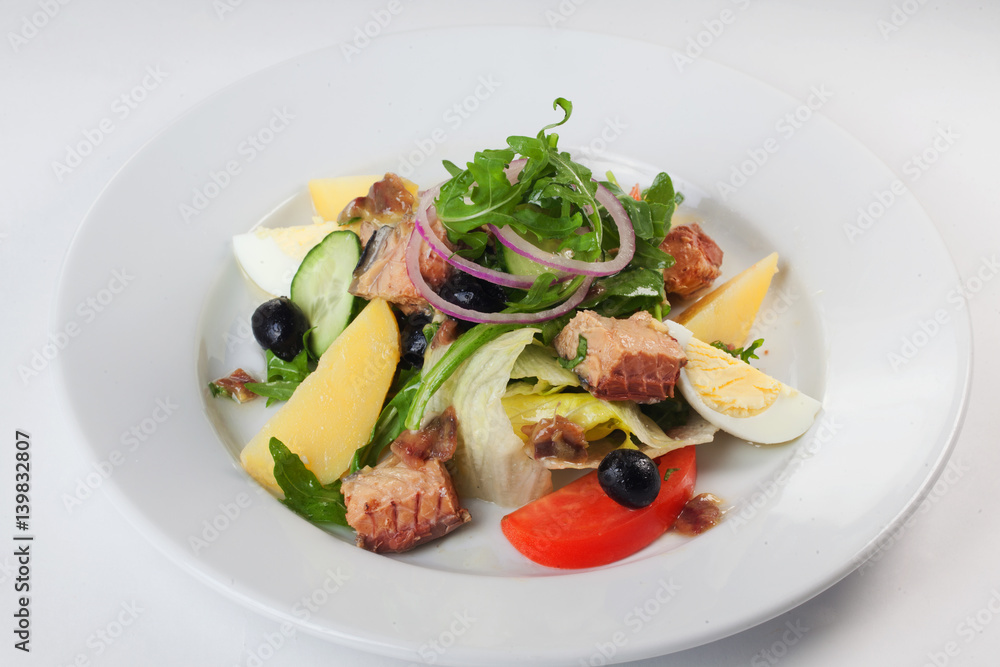 Fish salad, arugula, potatoes, onion, olives on a white background isolated for menu Fish salad, arugula, potatoes, onion, olives on a white background isolated for menu