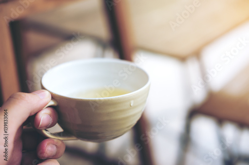 Hand holding clay tea mug with vintage wooden table