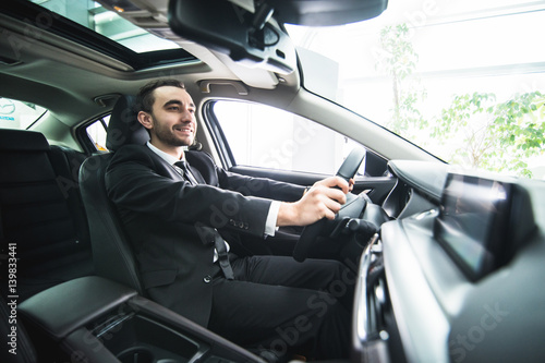 Driving with pleasure. Close-up of cheerful mature man in formalwear driving car and smiling © F8  \ Suport Ukraine