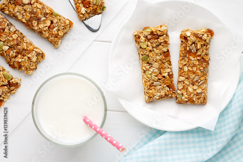 Homemade cereal snacks for healthy eating. Granola bars with milk on white wooden background.