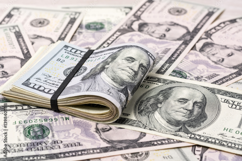 A stack of one hundred dollar bills on a background of dollars 