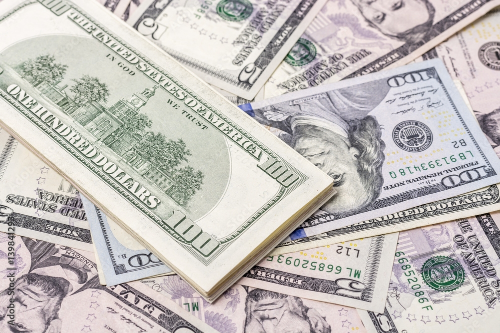 A stack of one hundred dollar bills on a background of dollars 