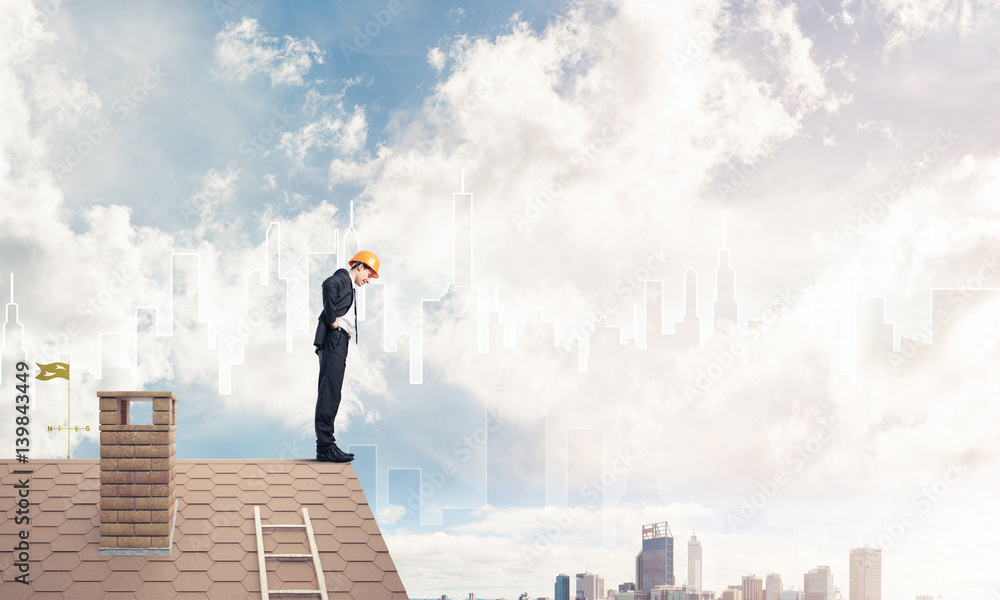 Engineer man standing on roof and looking down. Mixed media Engineer man standing on roof and looking down. Mixed media