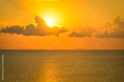 sun hides behind clowds dramatic and colorful sunset at beach