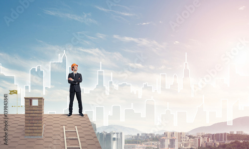 Engineer man standing on roof and looking away. Mixed media