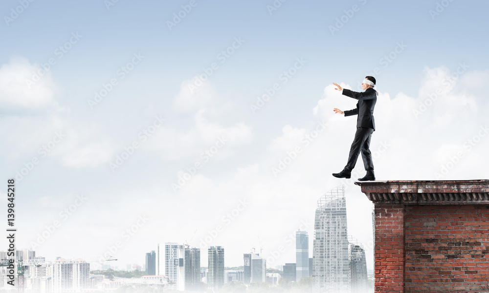 Danger and risk concept with businessman making step from edge Danger and risk concept with businessman making step from edge