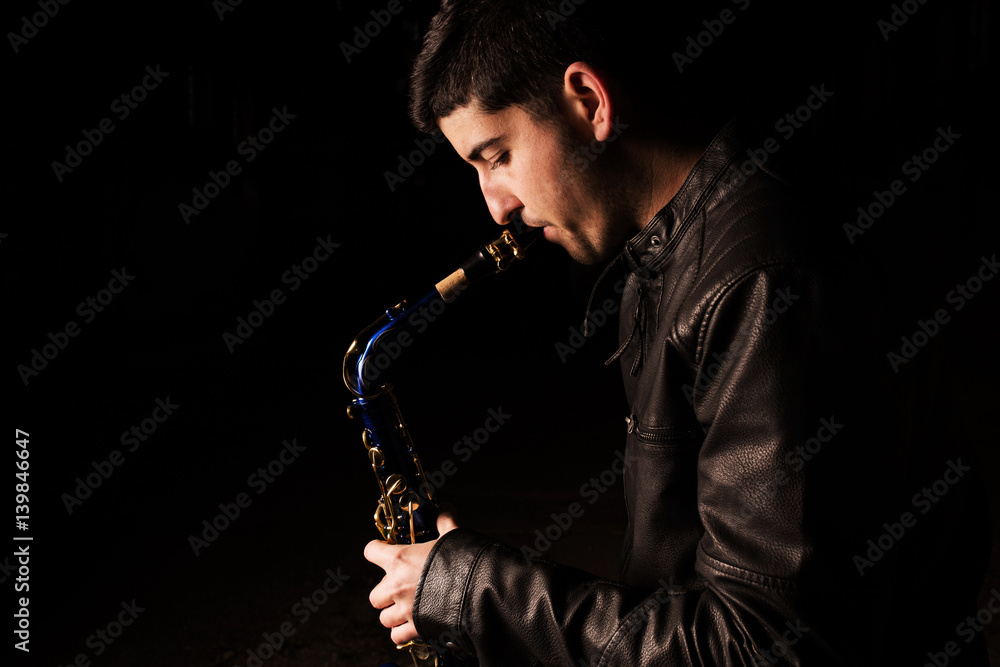Naklejka premium Man playing saxophone, with black background