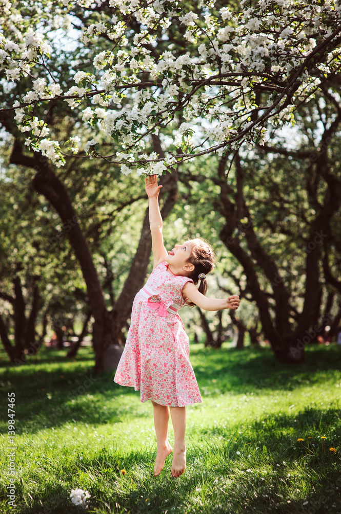 spring portrait of cute smiling child girl with blooming cherries