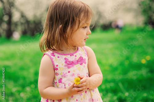 cute little happy toddler girl portrait walking in spring or summer park or garden