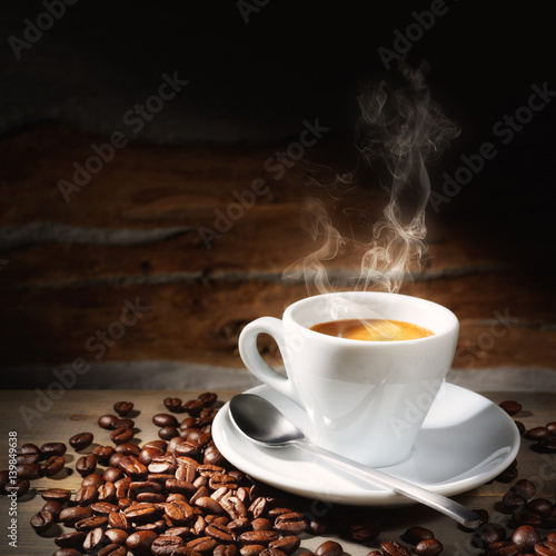 Steaming espresso cup and coffee beans in rustic setting, closeup, space for text.
