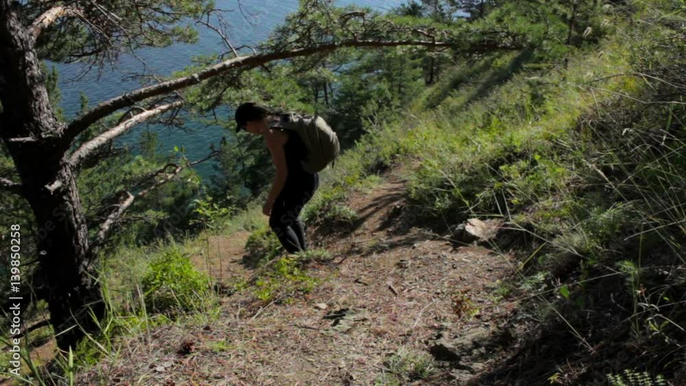 Girl coming down the steep mountainside to ocean. Young woman descend to the sea Girl coming down the steep mountainside to ocean. Young woman descend to the sea