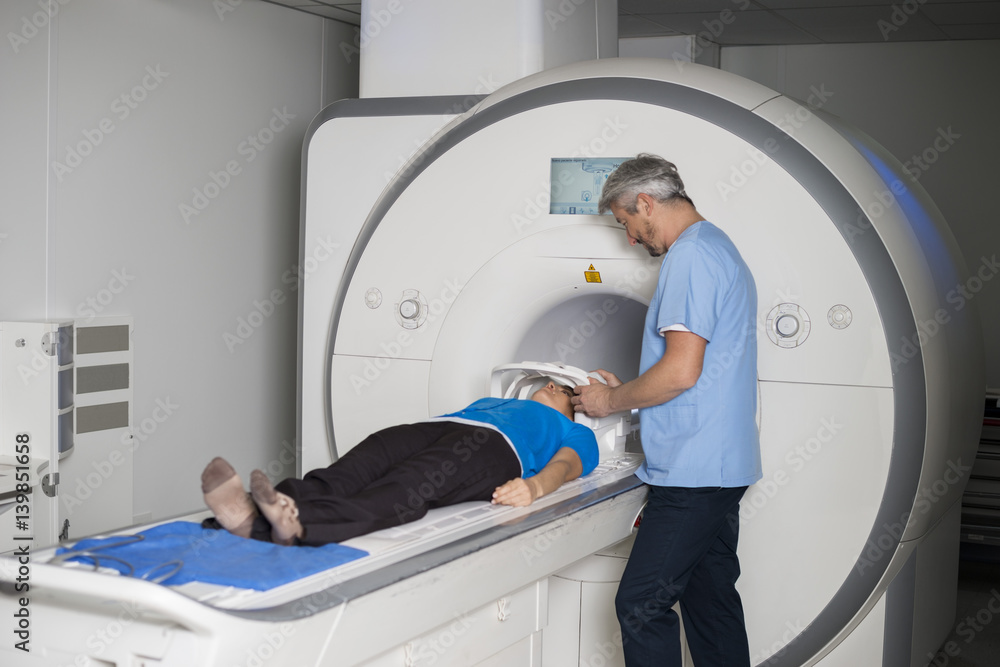 Doctor Fixing Mask To Female Patient Lying CT Scan Machine Doctor Fixing Mask To Female Patient Lying CT Scan Machine