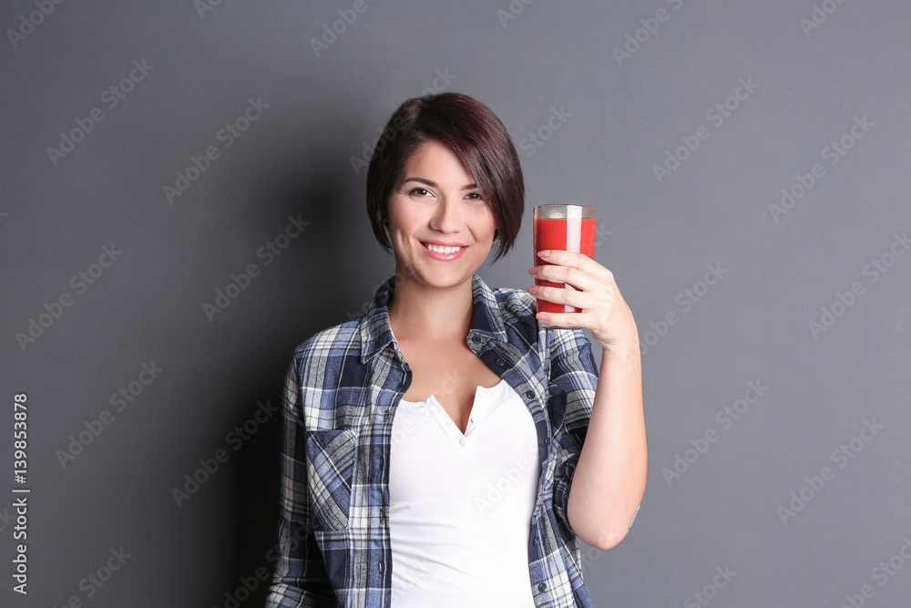 Young beautiful woman with glass of tomato juice, on grey background Young beautiful woman with glass of tomato juice, on grey background