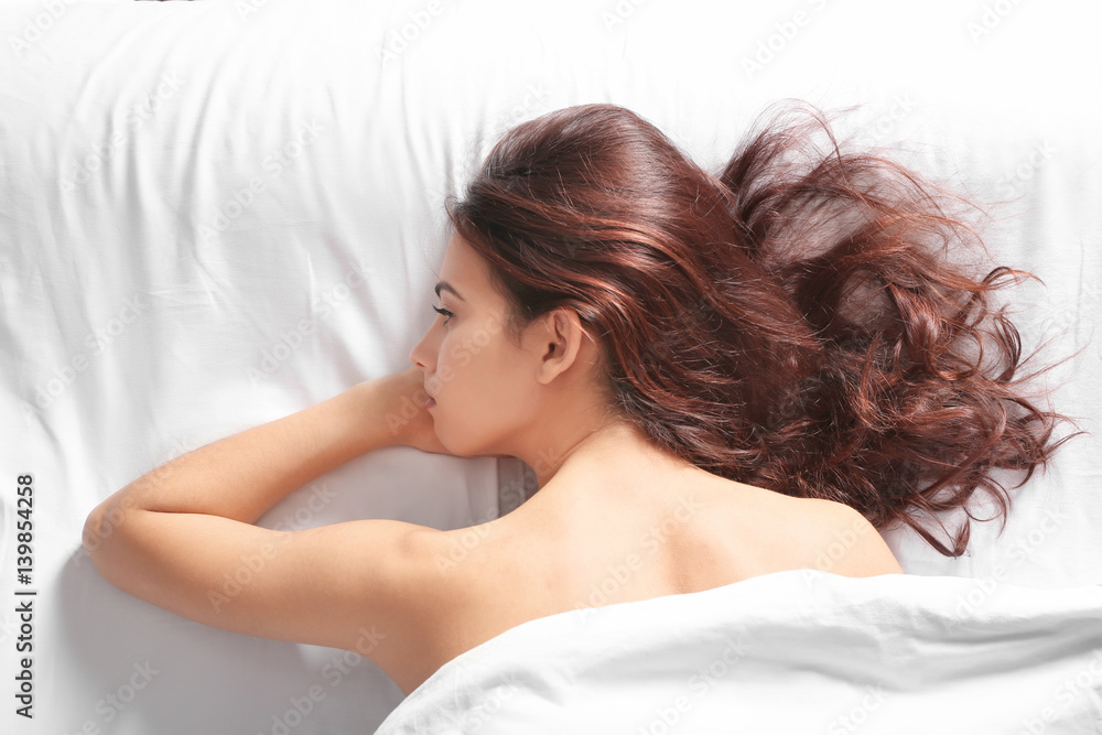 Depressed young woman lying on bed at home Depressed young woman lying on bed at home