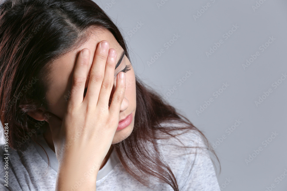 Young woman suffering from headache on color background, closeup Young woman suffering from headache on color background, closeup