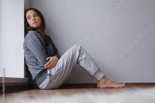 Картината върху платно Depressed young woman sitting on floor in empty room