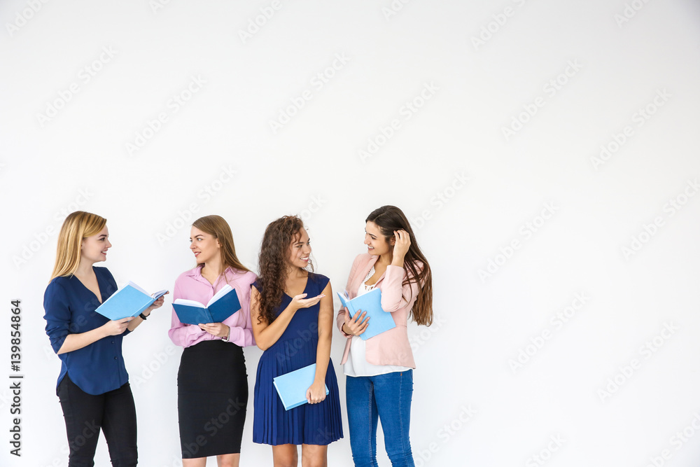 Beautiful young women with books on light background