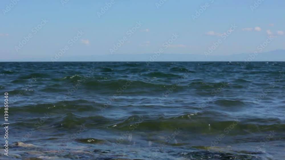 Calm surf on the Lake Baikal. Small waves splash about shore. Sea, ocean, water Calm surf on the Lake Baikal. Small waves splash about shore. Sea, ocean, water
