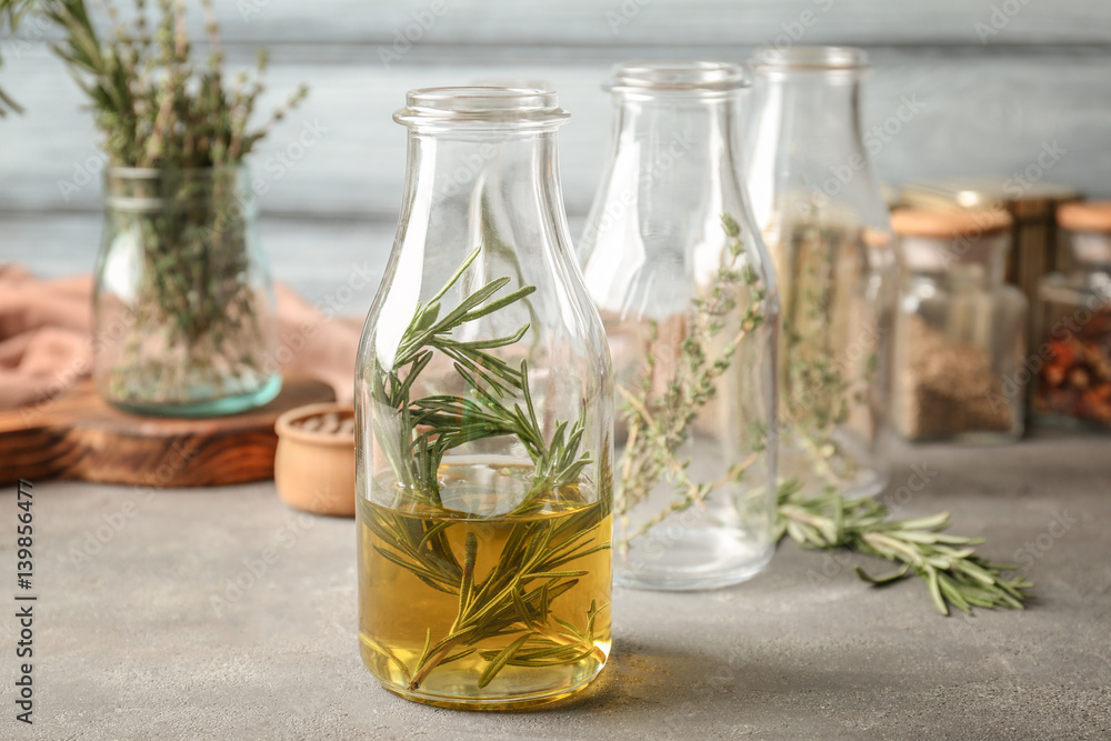 Bottle with rosemary and oil on table Bottle with rosemary and oil on table