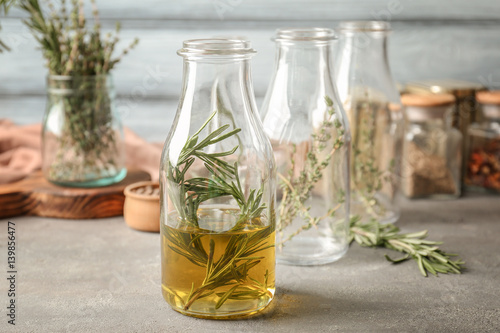 Bottle with rosemary and oil on table