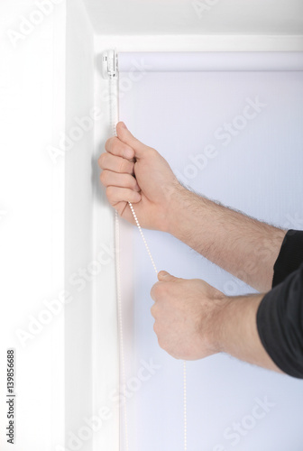 Male hands installing roller blinds on window