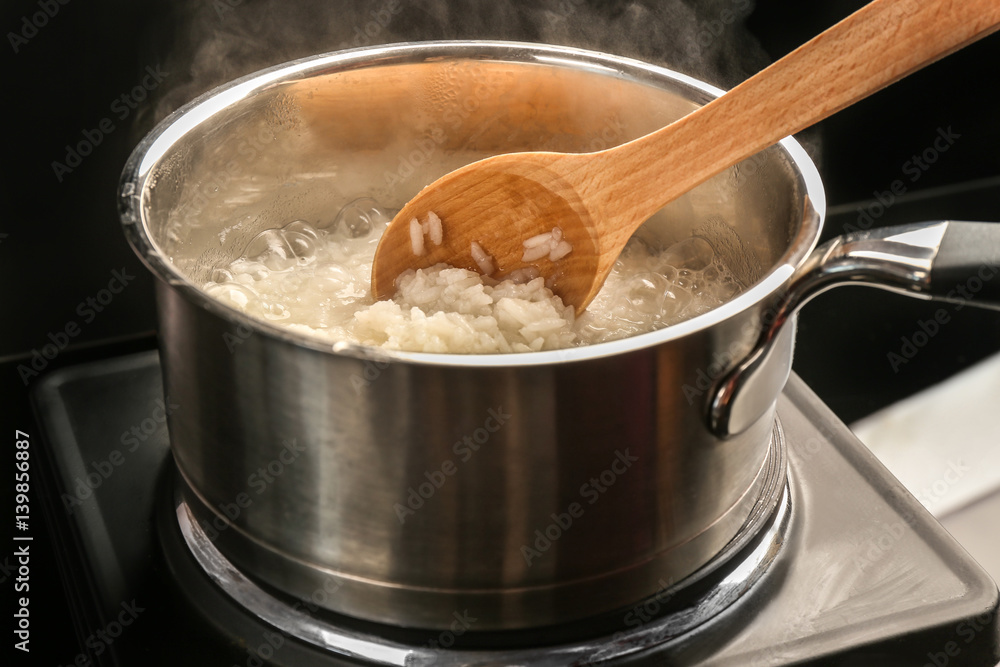 Cooking rice in metal pan on hotplate in kitchen Cooking rice in metal pan on hotplate in kitchen