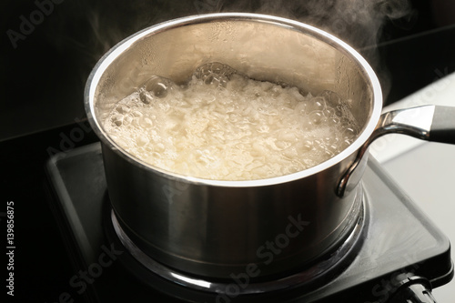 Cooking rice in metal pan on hotplate in kitchen