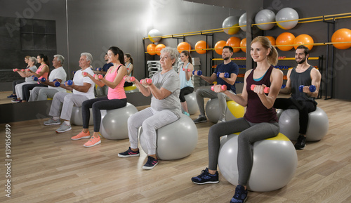 People of different ages training with fit balls in gym