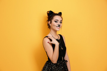 Beautiful young woman with cat makeup and ears on color background