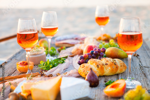 Picnic on the beach at sunset in boho style, food and drink concept