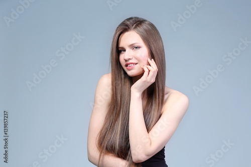 Attractive young woman with beautiful long hair on light background