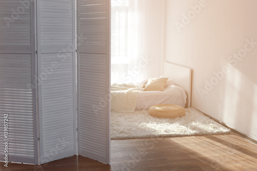 Interior of beautiful room with folding screen and bed