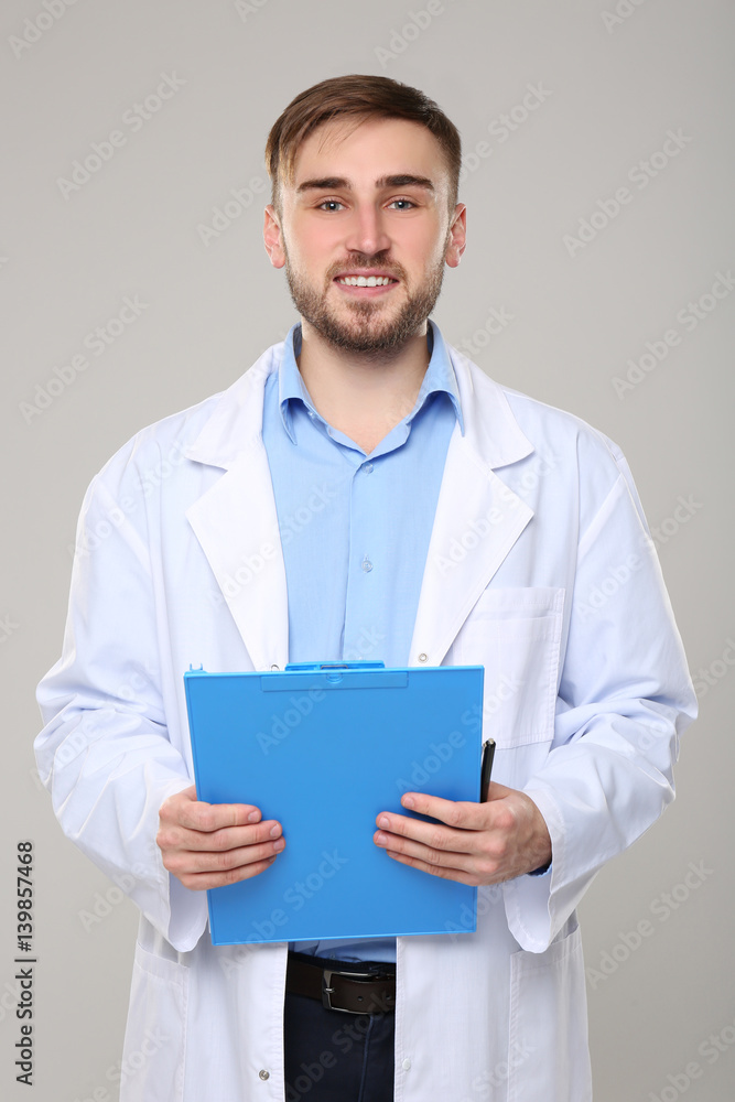 Handsome doctor with blue clipboard on light background Handsome doctor with blue clipboard on light background