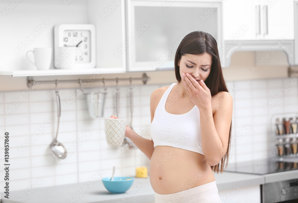 Beautiful pregnant woman suffering of nausea in kitchen Beautiful pregnant woman suffering of nausea in kitchen