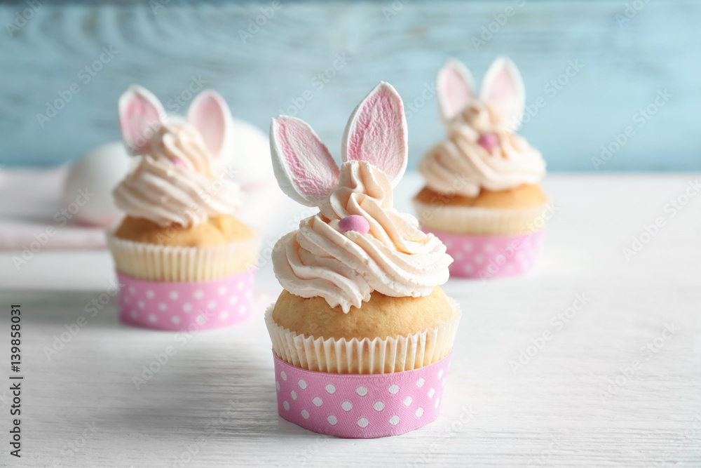 Fototapeta premium Decorated Easter cupcakes on white wooden table