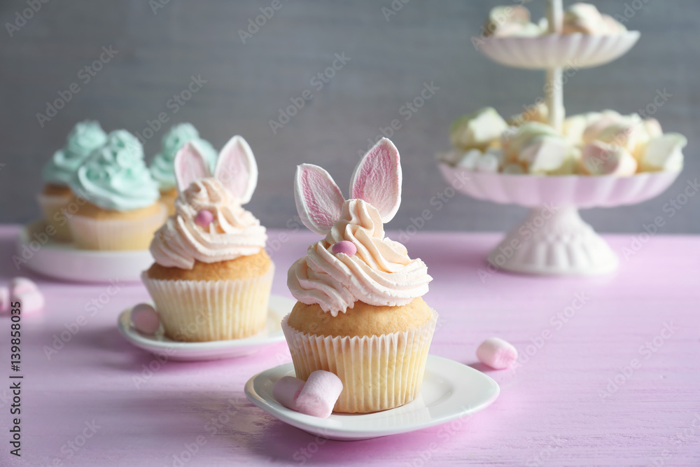 Tasty Easter cupcakes on pink wooden table against grey background Tasty Easter cupcakes on pink wooden table against grey background