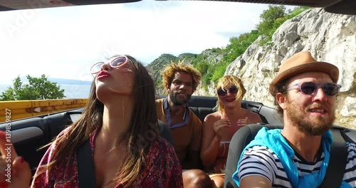 Attractive young people enjoying music while driving in convertible 