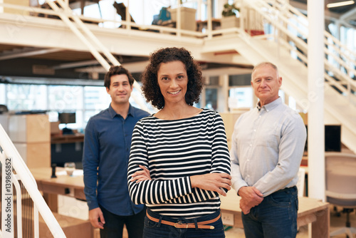 Smiling businesswoman in an office with coworkers standing behind her