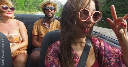 Beautiful young woman having fun driving her friends in convertible
