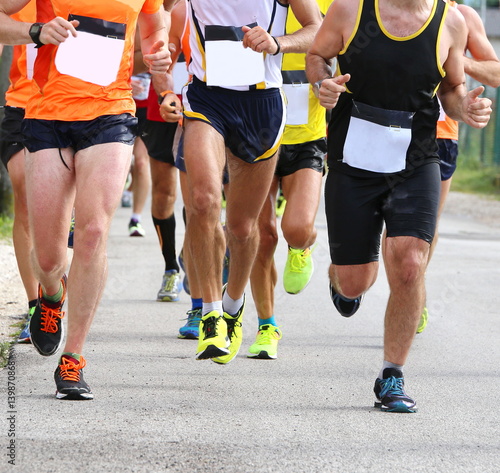 muscular legs of runners during sports race through the streets © ChiccoDodiFC