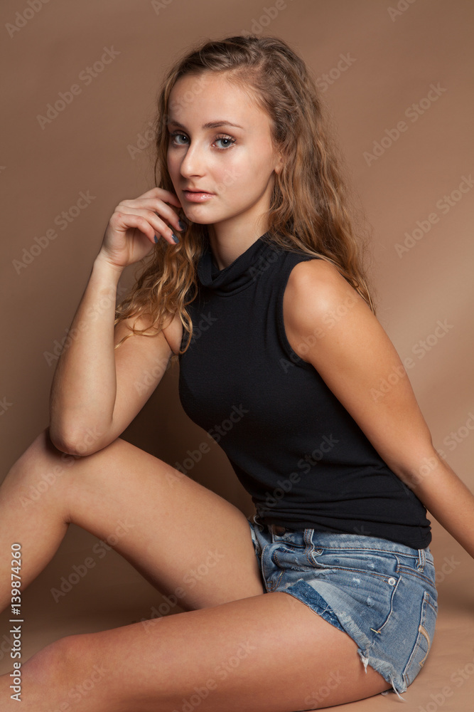 Seated Teen in Jean Shorts and Top Photos | Adobe Stock