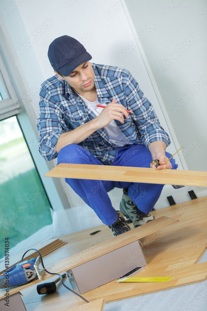 young handyman fitting wooden floor at construction site young handyman fitting wooden floor at construction site