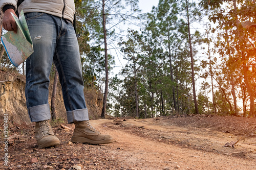 Lonely man wearing jeans and leather boots walking along the path strewn with rocks.