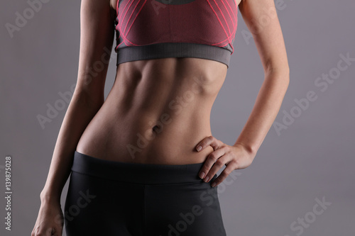 Sport, fit woman. Female with perfect abdomen muscles on grey background. Dieting, fitness, active lifestyle concept, copy space © dream@do