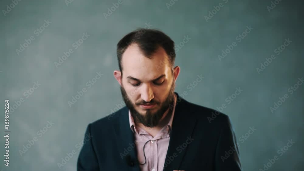 Young caucasian bearded man in blue business jacket and striped shirt with lavalier microphone on isolated background wall confidently explaining Young caucasian bearded man in blue business jacket and striped shirt with lavalier microphone on isolated background wall confidently explaining